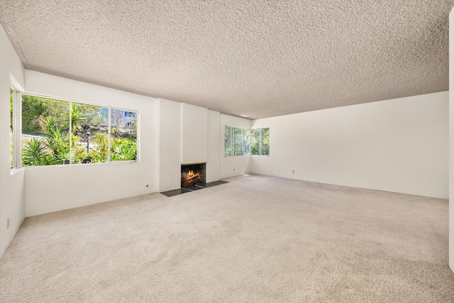 unfurnished living room with a fireplace with flush hearth, carpet, and a textured ceiling