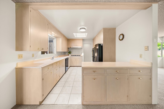 kitchen with light brown cabinets, light countertops, a peninsula, a skylight, and black appliances