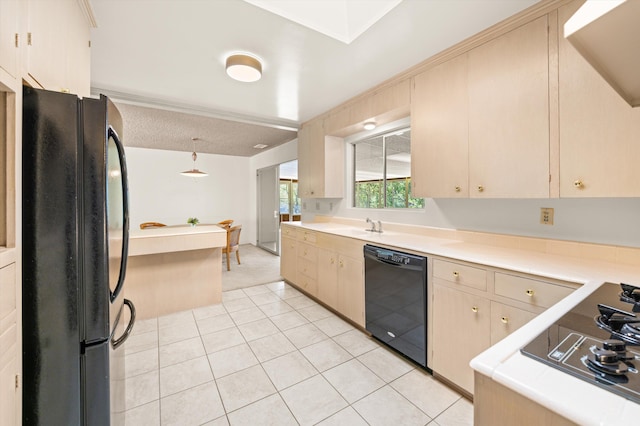 kitchen with light tile patterned flooring, a sink, light countertops, decorative light fixtures, and black appliances