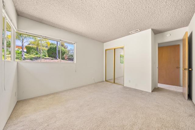 unfurnished bedroom featuring visible vents, a textured ceiling, carpet, and a closet