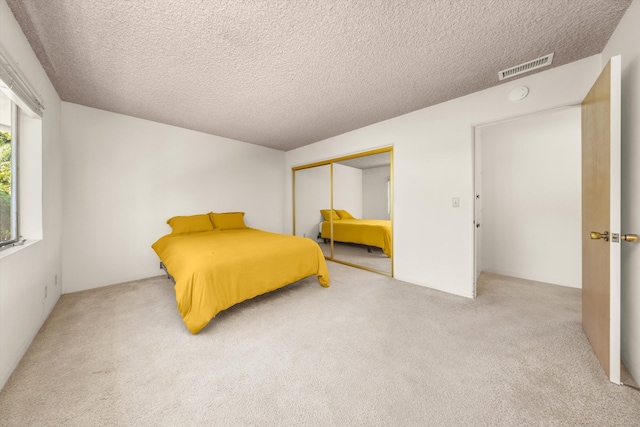 bedroom featuring visible vents, carpet, a textured ceiling, and a closet