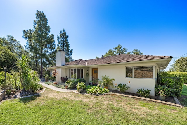view of front of home featuring a chimney, a front yard, and stucco siding