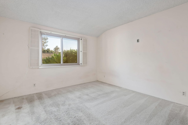 empty room featuring a textured ceiling, lofted ceiling, and carpet