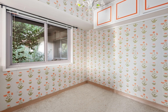 empty room featuring baseboards, wallpapered walls, an inviting chandelier, and carpet flooring