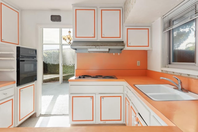kitchen with under cabinet range hood, light countertops, oven, white cabinets, and a sink