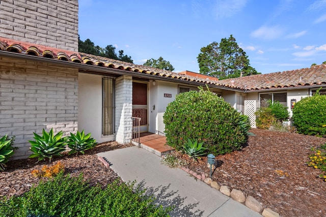 property entrance with stucco siding and a tiled roof