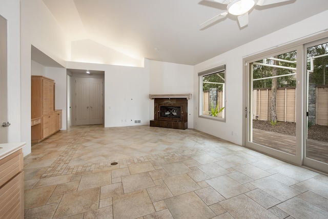 unfurnished living room with lofted ceiling, stone tile floors, plenty of natural light, and a ceiling fan
