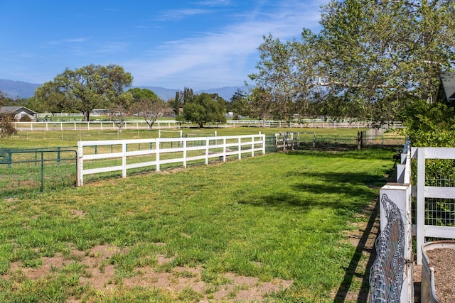 view of yard with fence, a rural view, and a mountain view