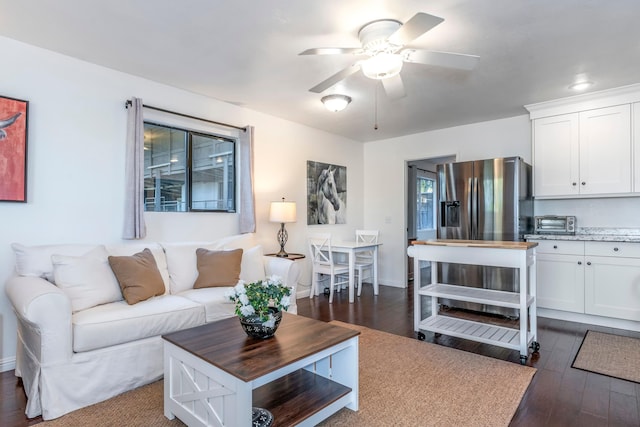 living area with a toaster, ceiling fan, dark wood-style floors, and baseboards
