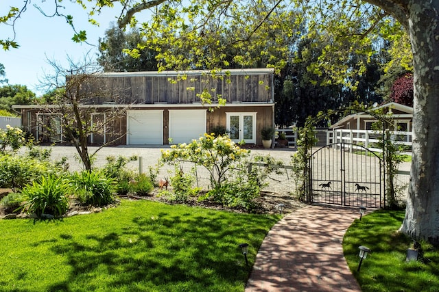 view of front of home featuring a gate, a front yard, fence, french doors, and a garage