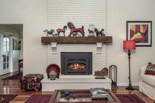 interior space with a brick fireplace, wood finished floors, and baseboards