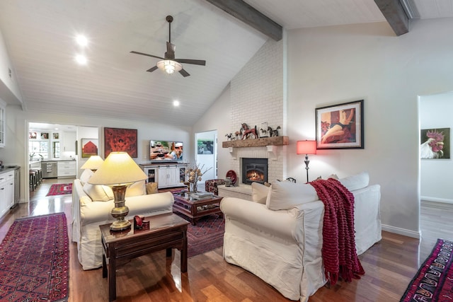 living area featuring a ceiling fan, vaulted ceiling with beams, wood finished floors, and a fireplace