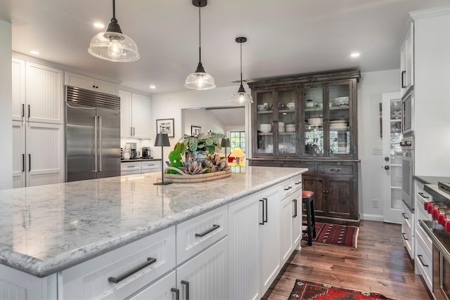 kitchen with white cabinetry, built in appliances, dark wood-style floors, light stone countertops, and recessed lighting