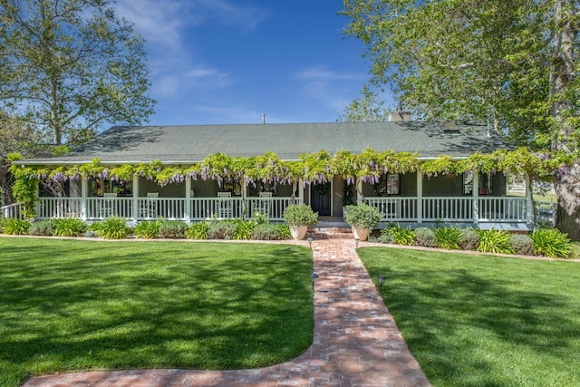 country-style home with covered porch, a front yard, and roof with shingles
