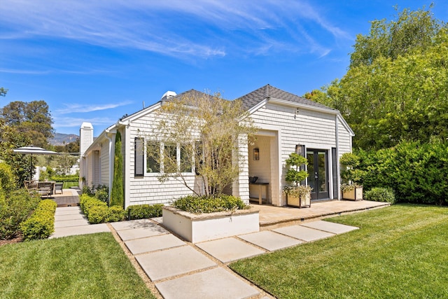bungalow-style home with a chimney, french doors, a wooden deck, and a front yard