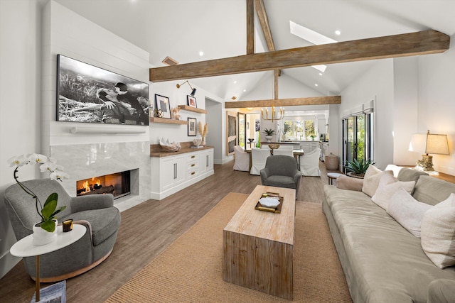 living area featuring a chandelier, beam ceiling, recessed lighting, a fireplace, and wood finished floors