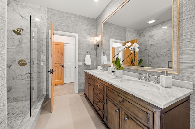 bathroom with a marble finish shower, a sink, and double vanity