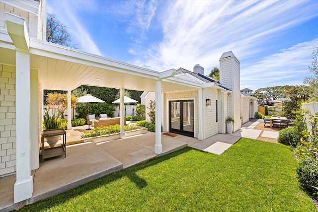 back of property with a lawn, a chimney, a patio, and an outdoor living space