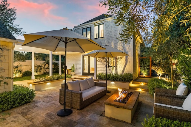 patio terrace at dusk with french doors and an outdoor living space with a fire pit