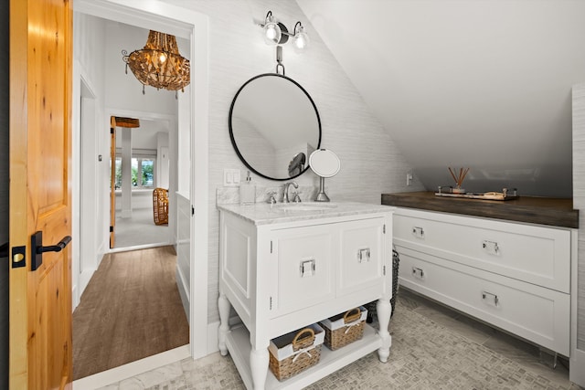 bathroom featuring an inviting chandelier, vanity, and vaulted ceiling