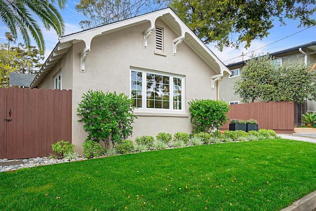 view of side of property with stucco siding, a yard, and fence