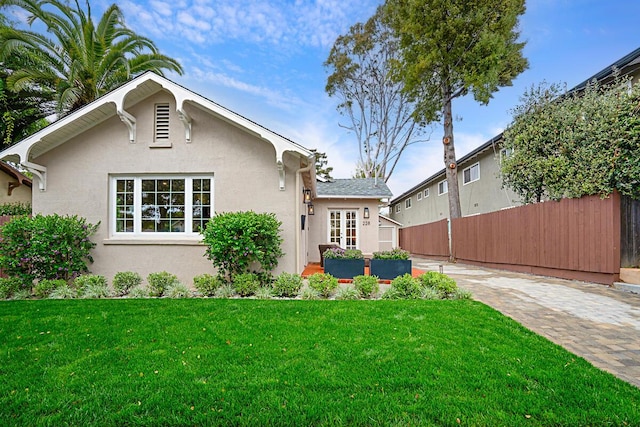 view of front of home featuring fence, a front lawn, and stucco siding