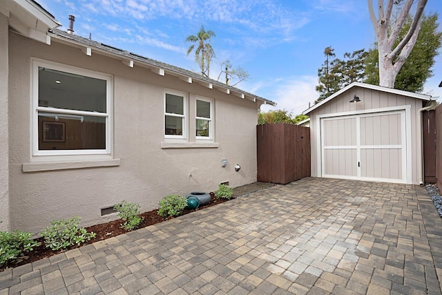 exterior space with fence, an outbuilding, decorative driveway, and a garage