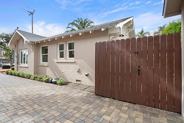 view of home's exterior featuring fence, a gate, stucco siding, and a patio area