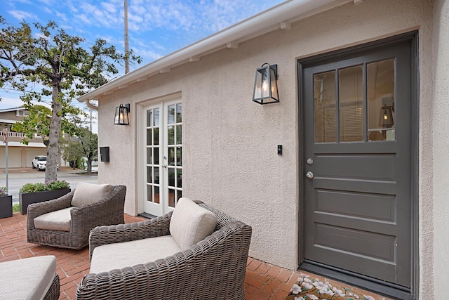 property entrance with french doors, stucco siding, and a patio area