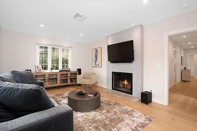 living room featuring visible vents, a fireplace, baseboards, recessed lighting, and light wood-style flooring