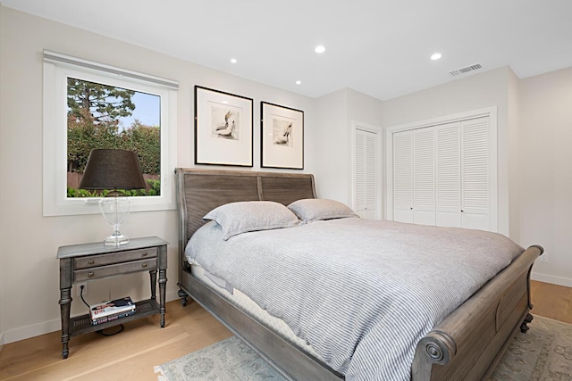 bedroom with recessed lighting, baseboards, wood finished floors, visible vents, and a closet