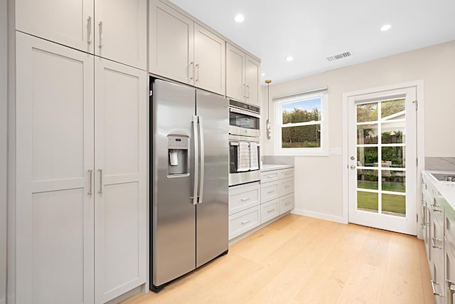 kitchen featuring light countertops, stainless steel appliances, recessed lighting, light wood-type flooring, and visible vents