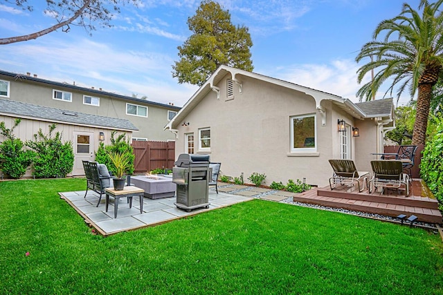 rear view of property with fence, stucco siding, a deck, a patio area, and a yard
