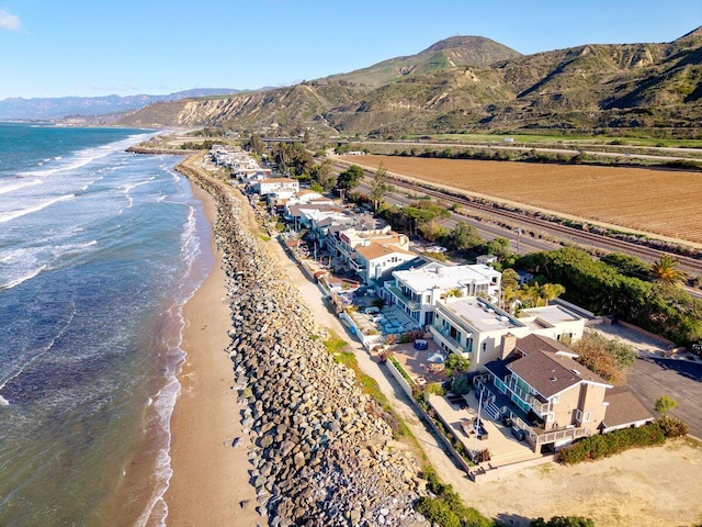 drone / aerial view featuring a water and mountain view and a beach view