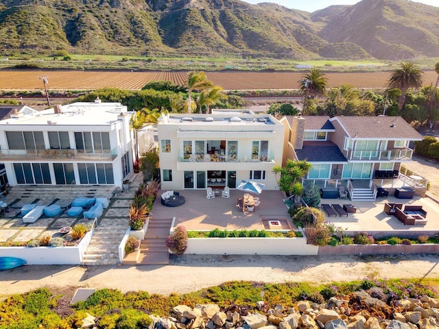 exterior space featuring stairs, stucco siding, a mountain view, a balcony, and a patio