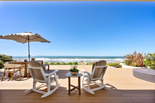 wooden deck featuring a beach view and a water view