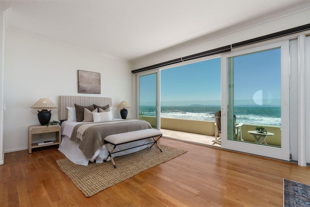 bedroom featuring crown molding, a water view, wood finished floors, and access to outside