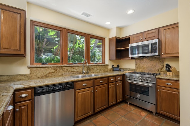 kitchen featuring a sink, brown cabinetry, stainless steel appliances, tasteful backsplash, and visible vents
