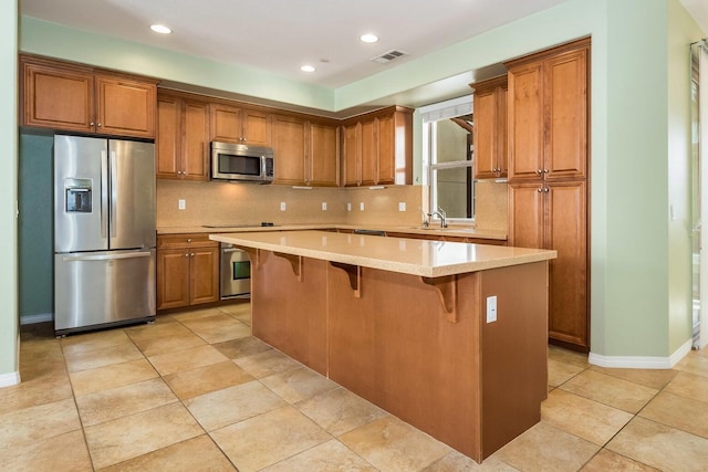 kitchen with a center island, a sink, appliances with stainless steel finishes, and brown cabinets