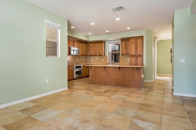 kitchen featuring stainless steel appliances, baseboards, a breakfast bar, and visible vents