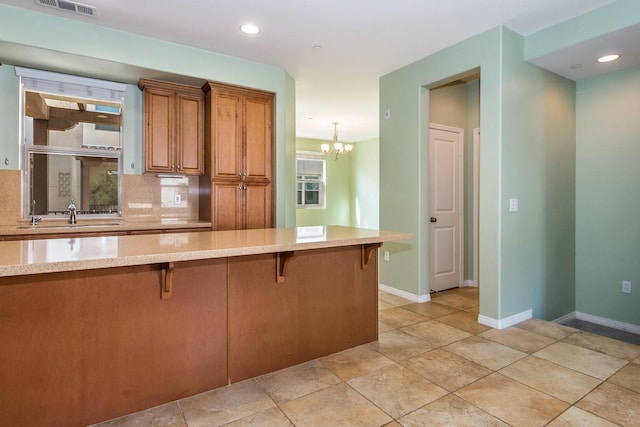 kitchen featuring a sink, baseboards, a kitchen breakfast bar, and brown cabinetry