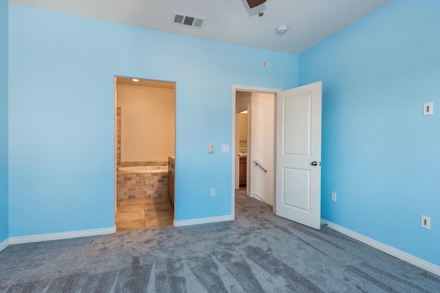 unfurnished bedroom with visible vents, carpet flooring, baseboards, and ensuite bathroom