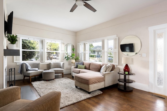 living room featuring baseboards, dark wood finished floors, ceiling fan, and visible vents
