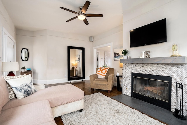 living area with baseboards, a ceiling fan, wood finished floors, and a tile fireplace