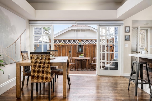 dining room with baseboards, wood finished floors, and a raised ceiling