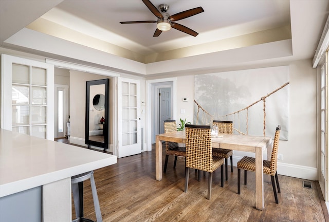 dining space with visible vents, a raised ceiling, ceiling fan, and baseboards