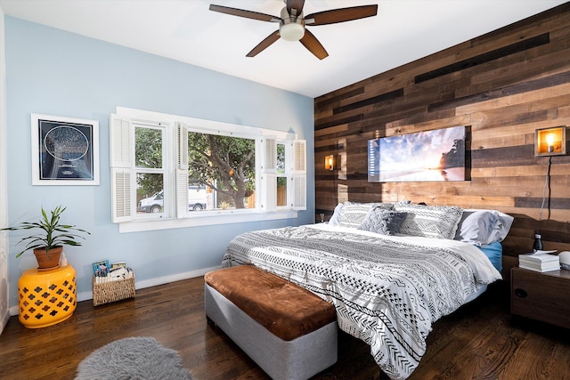bedroom with baseboards, a ceiling fan, wood finished floors, and wooden walls