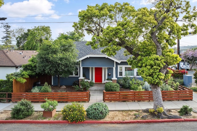 view of front of home with a shingled roof and a fenced front yard