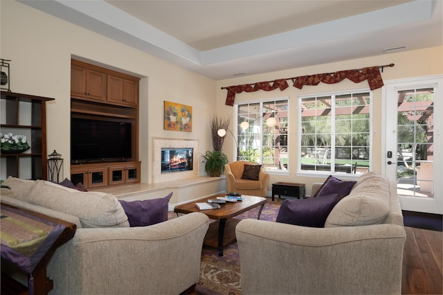 living area featuring a glass covered fireplace, plenty of natural light, visible vents, and dark wood-type flooring
