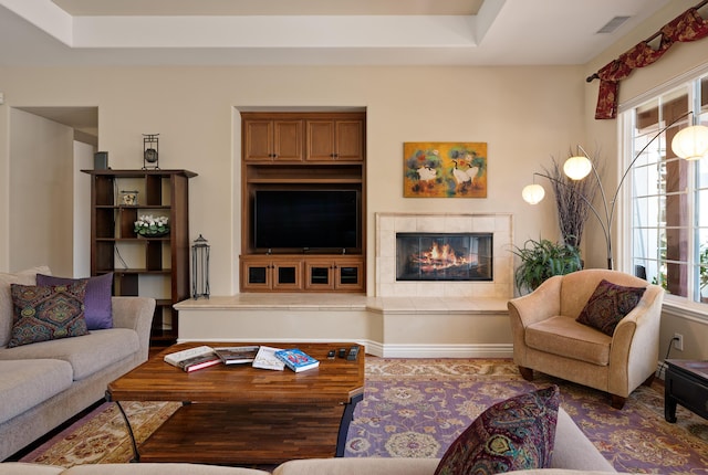 living area with a tray ceiling, a wealth of natural light, and a fireplace